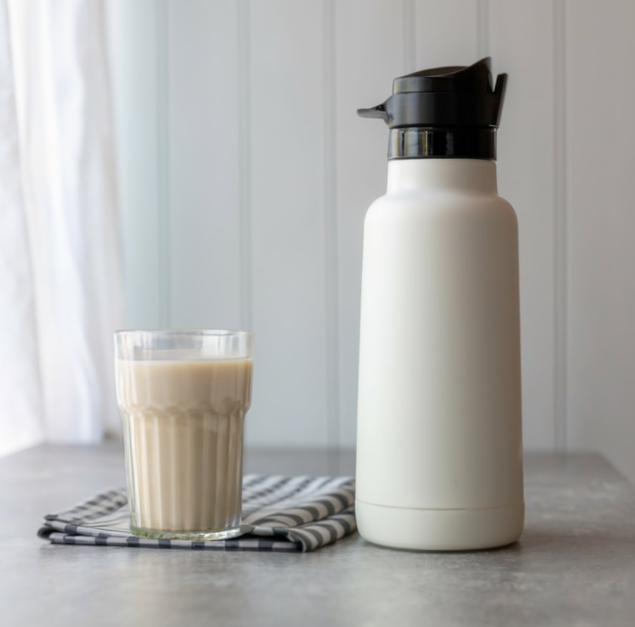 A thermos flask and a glass of milk on a table